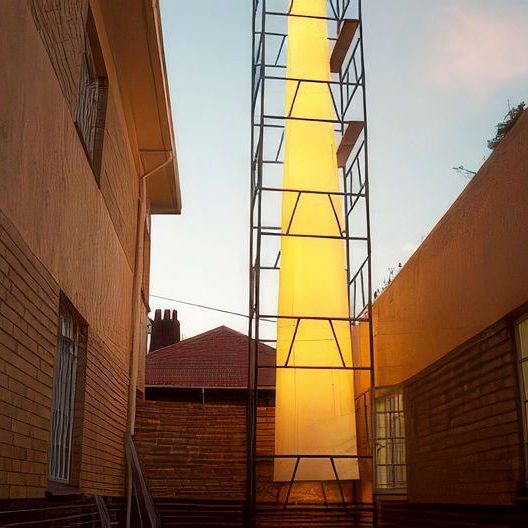 Tall illuminated exterior light column between two buildings
